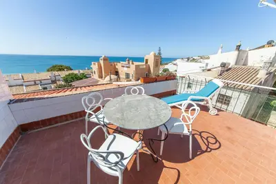 a patio with a table and chairs and the ocean at Casas da Calheta in Praia da Luz in Luz