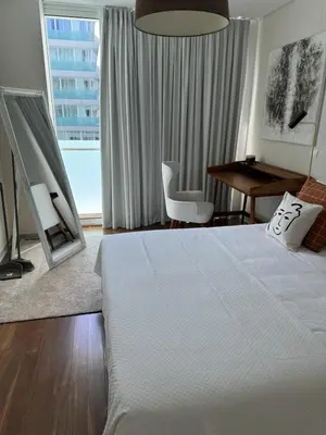 a bedroom with a bed and a desk and a window at Plaza Funchal - Coração da cidade in Funchal