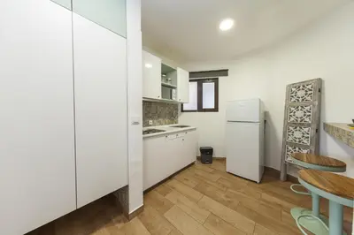 a kitchen with white cabinets and a table and a refrigerator at A18 - Luz Studio in Praia da Luz in Luz