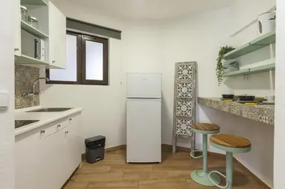 a white kitchen with a refrigerator and two stools at A18 - Luz Studio in Praia da Luz in Luz