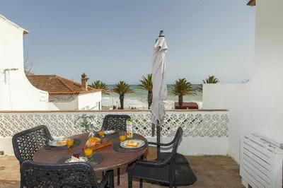 a wooden table with chairs and an umbrella on a patio at B86 - Beachline Apartment in Praia da Luz in Luz
