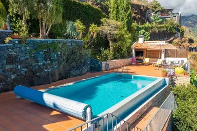 a swimming pool in a yard with a patio and a house at Villa Tabua in Ribeira Brava
