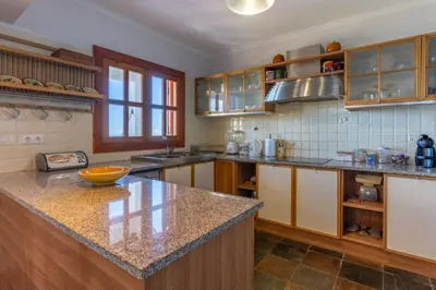 a kitchen with wooden cabinets and a granite counter top at Villa Tabua in Ribeira Brava