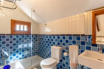 a blue tiled bathroom with a toilet and a sink at Villa Tabua in Ribeira Brava