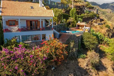 a house on a hill with flowers and a swimming pool at Villa Tabua in Ribeira Brava