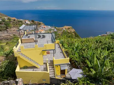 a yellow house on a hill overlooking the ocean at Sky & Ocean in Calheta