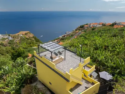 a yellow house on top of a hill with the ocean at Sky & Ocean in Calheta
