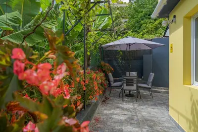 a patio with an umbrella and chairs and flowers at Sky & Ocean in Calheta