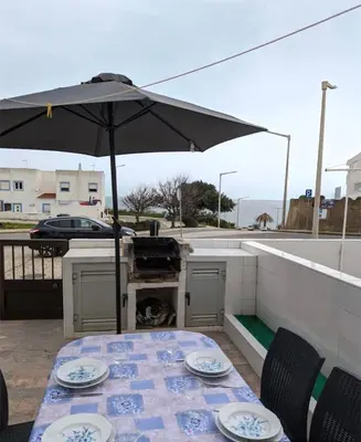 a table with an umbrella on a patio at Casa do Mar in Salema