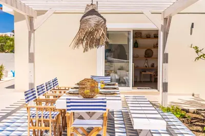a table with blue and white chairs on a patio at Casa do Cacto - By WeHost in Porto Santo
