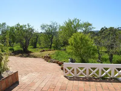 a white bench sitting on a brick walkway at Monte Rosa Rural Guesthouse in Lagos