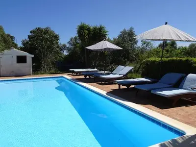 a swimming pool with chairs and umbrellas next to it at Monte Rosa Rural Guesthouse in Lagos
