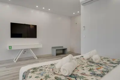 a white room with a bed with a flat screen tv at Torre Palace I by Atlantic Holiday in Câmara de Lobos