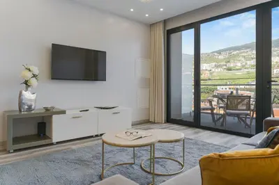 a living room with a tv and a couch and a table at Torre Palace I by Atlantic Holiday in Câmara de Lobos