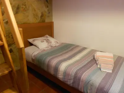 a small bed with a striped blanket and a pillow at Monte Chabouco - Alojamento Local in Chabouco