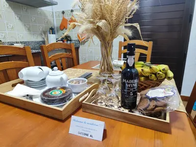a table with a bottle of wine and a basket of fruit at GATEONE AL Airport View House in Machico