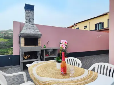 a table and chairs on a patio with a fireplace at GATEONE AL Airport View House in Machico
