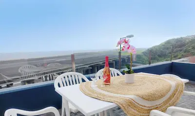 a table on a balcony with a view of the ocean at GATEONE AL Airport View House in Machico