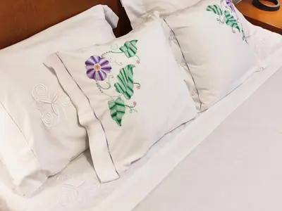 two white pillows with a purple flower on them on a bed at GATEONE AL Airport View House in Machico