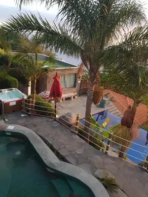 a swimming pool next to a fence with palm trees at Dazkarizeh73 in Ribeira Brava