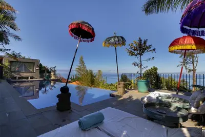 a house with a swimming pool with umbrellas at Dazkarizeh73 in Ribeira Brava
