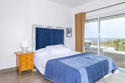 a bedroom with a bed with a blue blanket and a window at Villa Céu Do Sul in Burgau