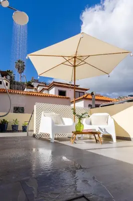 a patio with a table and an umbrella at Fisherhouse23 in Câmara de Lobos