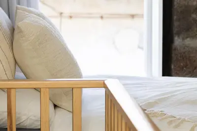 a bed with white sheets and pillows next to a window at Fisherhouse23 in Câmara de Lobos