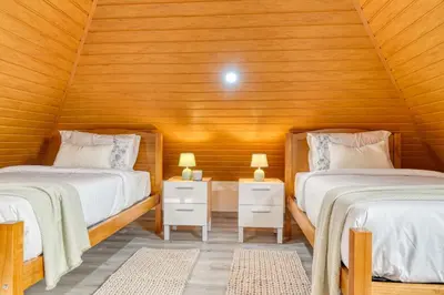 two beds in a room with wooden walls at Atlantic View, a Home in Madeira in Ponta do Sol