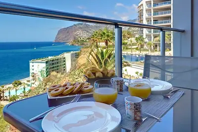 a table with plates of food and glasses of orange juice at Southern Skies Apartment in Funchal