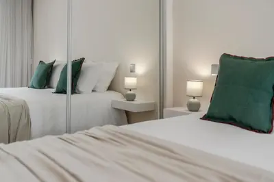 a bedroom with two beds with green pillows and mirrors at Santa Luzia III by An Island Apart in Funchal