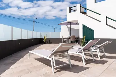 a patio with chairs and an umbrella on a roof at Atouguia House - Traditional House in Calheta