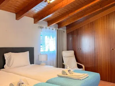 a bedroom with a bed and a chair with towels on it at Refúgio na Praia de Burgau #1947 in Burgau
