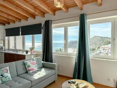 a living room with a couch and large windows at Refúgio na Praia de Burgau #1947 in Burgau