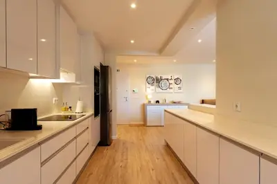 a kitchen with white cabinets and a wooden floor at The Jolie - Lava Pools Apartments in Porto Moniz