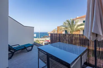 a balcony with a blue table and a view of the ocean at The Jolie - Lava Pools Apartments in Porto Moniz
