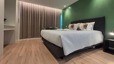 a bedroom with a large bed and a green wall at The Jolie - Lava Pools Apartments in Porto Moniz