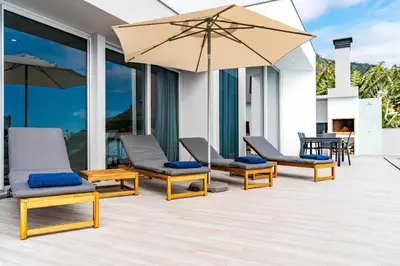 a patio with chairs and an umbrella at Villa Anita ,beautiful sunset in Arco da Calheta