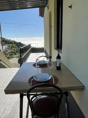 a wooden table with a glass of wine on it at Fernanda's House in Ribeira Brava