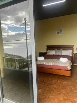 a bedroom with a bed and a balcony at Fernanda's House in Ribeira Brava