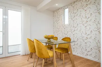 a dining room with a glass table and yellow chairs at Casa Magnólia in Funchal