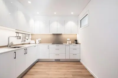 a white kitchen with white cabinets and a wooden floor at Casa Magnólia in Funchal