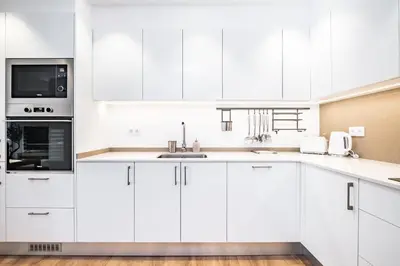 a white kitchen with white cabinets and a sink at Casa Magnólia in Funchal