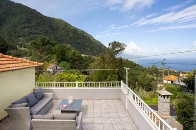 a patio with a couch and a table on a balcony at Casa Estrela Do Norte in Ponta Delgada