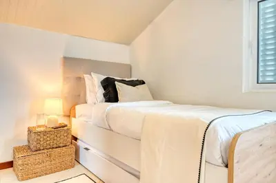 a white bedroom with a bed and a window at Cantinho da Mikaela, A Home in Madeira in Ponta do Sol