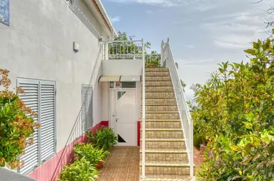 a stairway leading to a white building with a white door at Cantinho da Mikaela, A Home in Madeira in Ponta do Sol