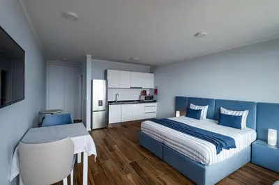a bedroom with a blue bed and a kitchen at Praia Encantada in Porto Santo