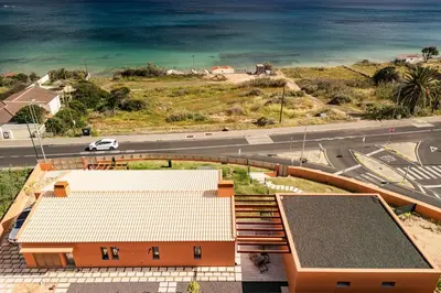 an aerial view of a building with a road and the ocean at Praia Encantada in Porto Santo