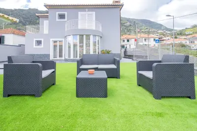a yard with four chairs and a table on grass at Villa Machico Valley in Machico