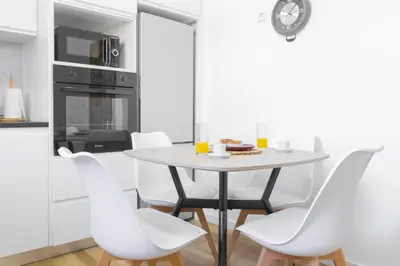 a white kitchen with a table and white chairs at Villa Machico Valley in Machico